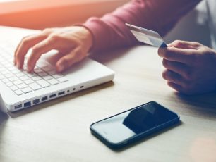 a person holding a credit card while using a laptop.
