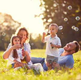 a family blowing bubbles in a field at sunset.