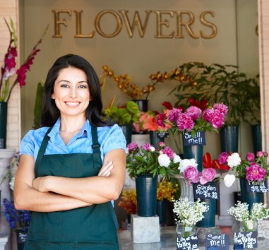 a woman standing in front of a flower shop.
